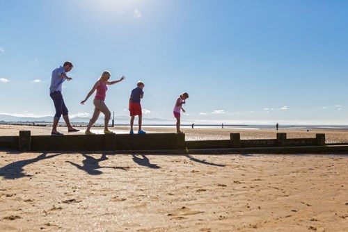 Family walking along groyne on Rhyl beach